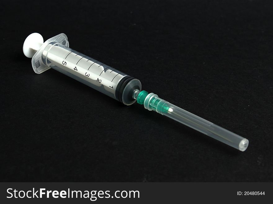 Packed syringe and needle with protector on black background