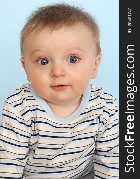 Surprized looking baby boy against a blue background. Surprized looking baby boy against a blue background