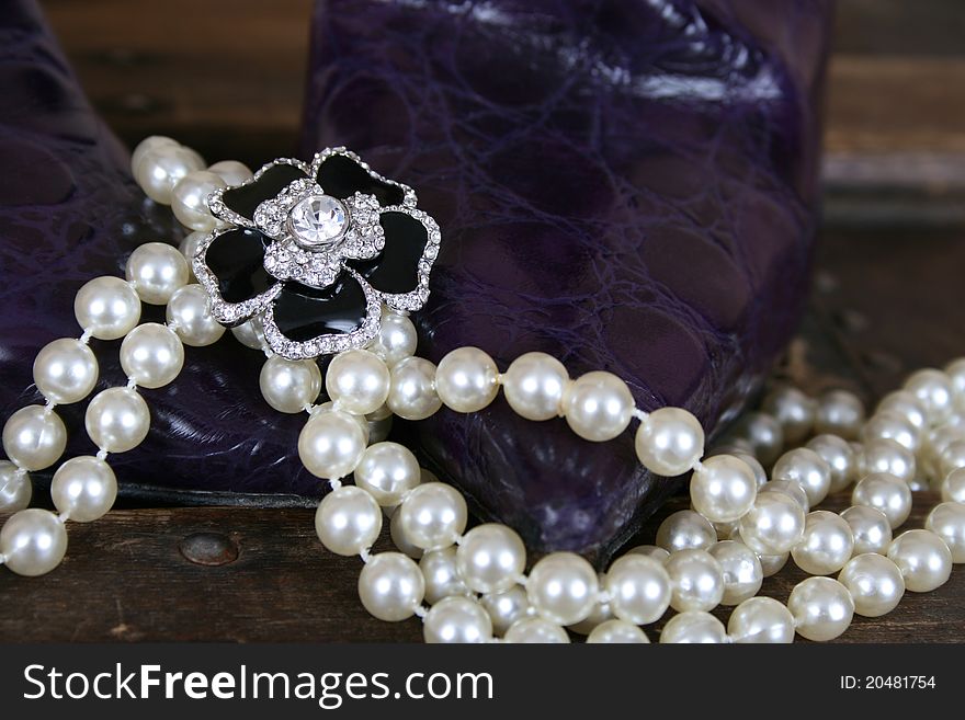 Pearls and jewellery with purple boots against antique trunk