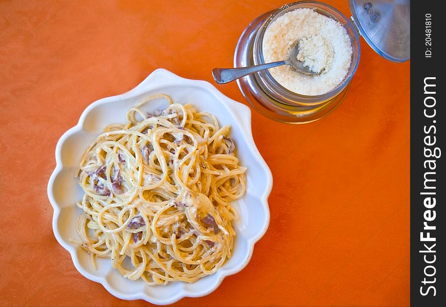 Plate with spaghetti alla carbonara and grated cheese