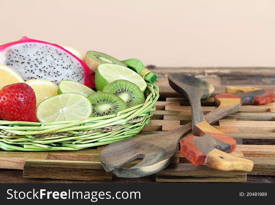 Green fruit basket on wooden placemat with spoons