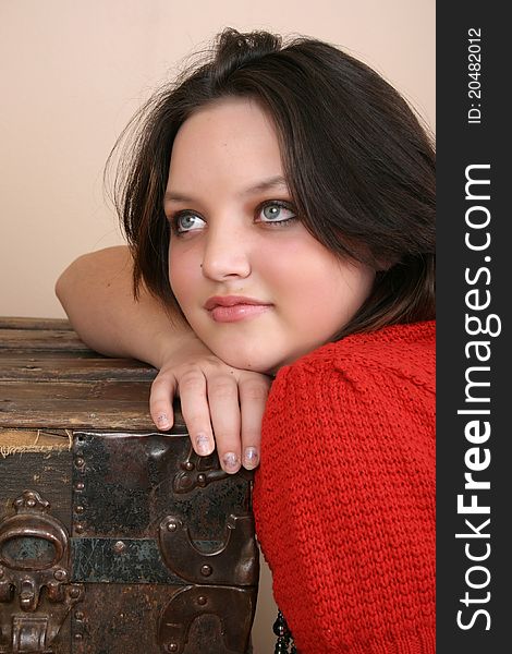 Beautiful brunette resting on antique wooden trunk. Beautiful brunette resting on antique wooden trunk