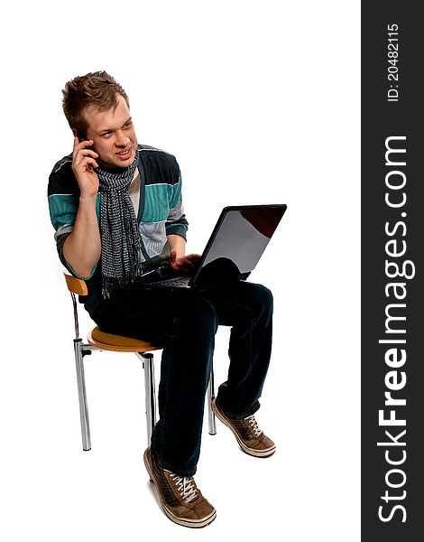 Young man with laptop and cell phone sitting in the studio posing on a white background. Young man with laptop and cell phone sitting in the studio posing on a white background