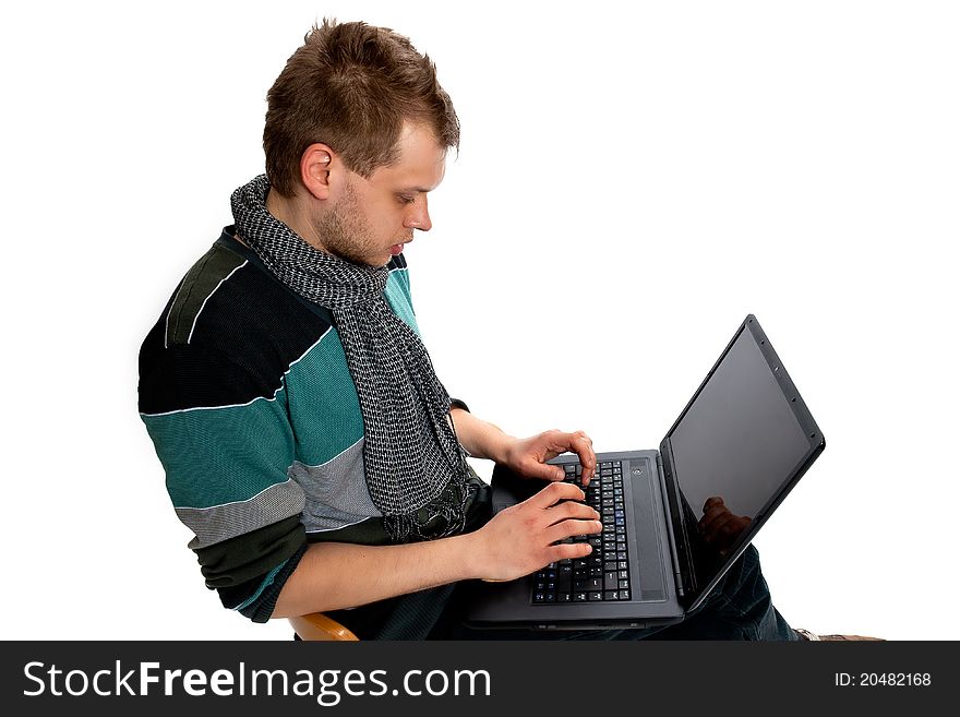 Young man with laptop sitting poses in the studio on a white background