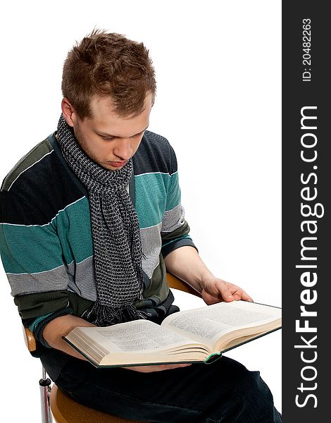 A young man sits reading a book in the studio posing on a white background. A young man sits reading a book in the studio posing on a white background