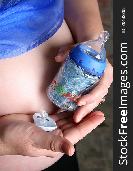 Heavily pregnant lady holding a bottle and dummy