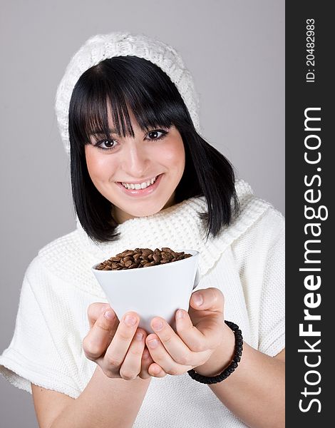 Beautiful young girl is holding a big white cup with coffee grains