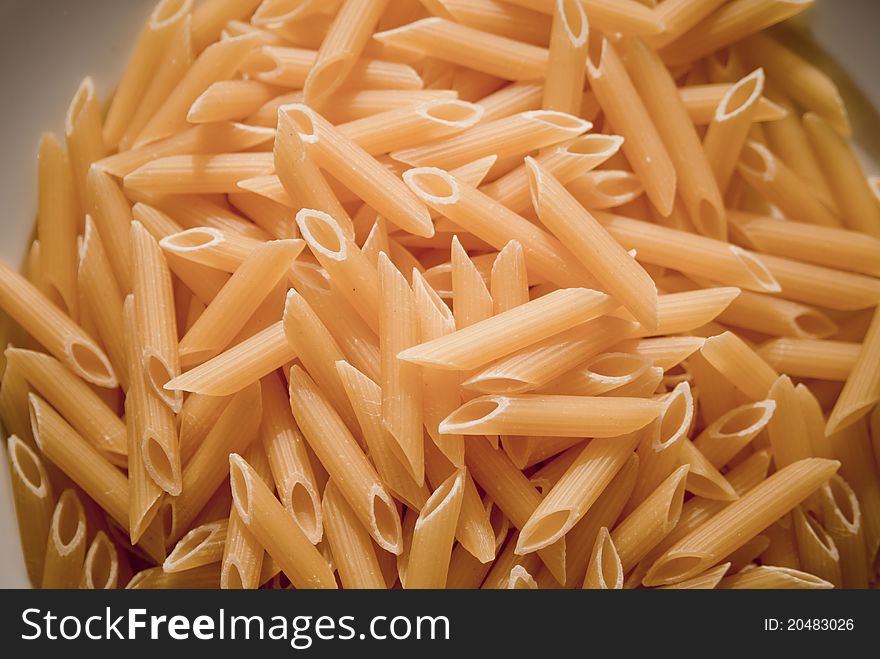 A plate of dried penne pasta shot in natural sunlight. A plate of dried penne pasta shot in natural sunlight