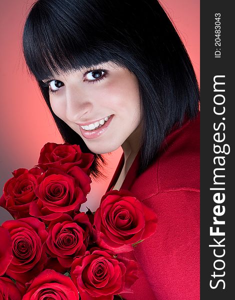 Beautiful young girl is holding a bouquet of  red roses