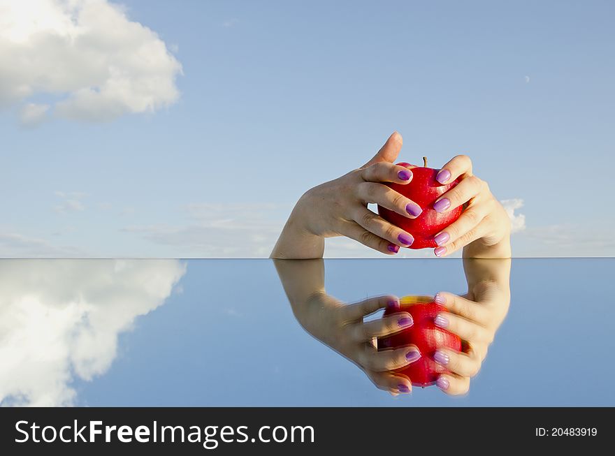 Womans hands holding red apple and mirror. Womans hands holding red apple and mirror