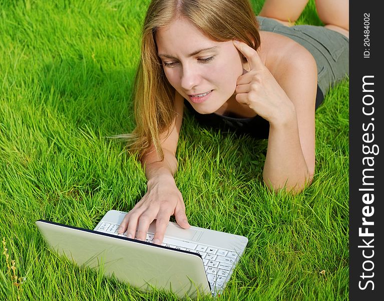 Girl with laptop lying on green grass. Girl with laptop lying on green grass