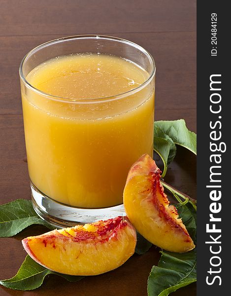 Juice to the peaches with slices of fruit on a wooden table. Juice to the peaches with slices of fruit on a wooden table