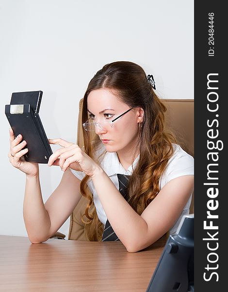 Girl in glasses pushes buttons on a calculator
