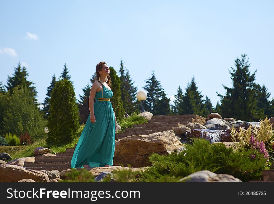 Beautiful brunette walking in the park next to a small waterfall