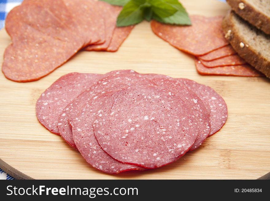 Salami with bread on edge board with mint