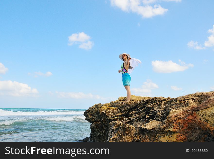 A girl stands on the beach and holding a white scarf that develops in the wind. A girl stands on the beach and holding a white scarf that develops in the wind