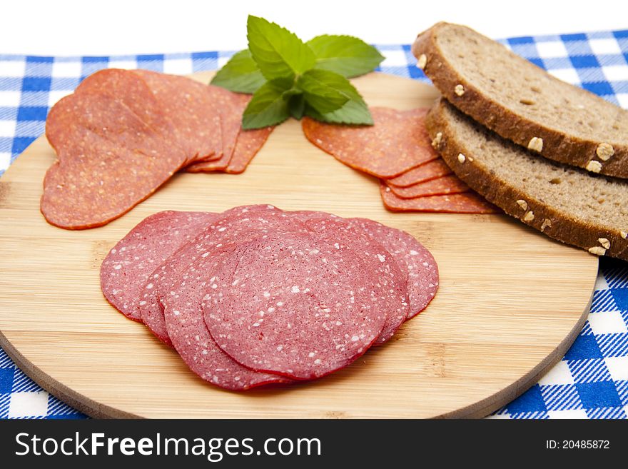 Salami with bread on edge board with mint