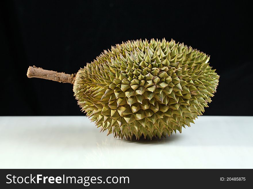 Close up of a durian on marble surface over black background.