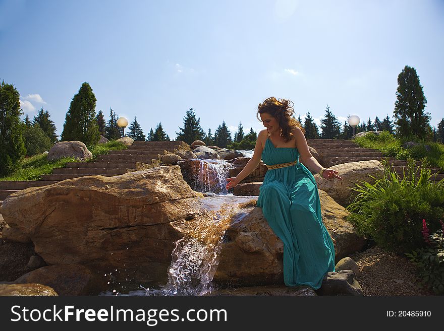 Beautiful brunette walking in the park next to a small waterfall