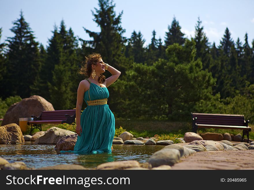 Beautiful brunette walking in the park next to a small waterfall