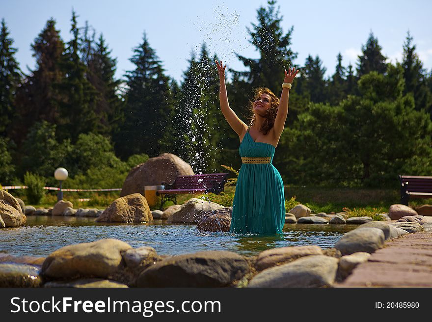 Beautiful brunette walking in the park next to a small waterfall