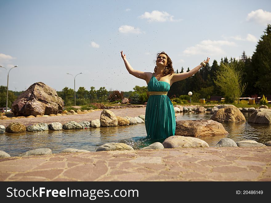 Beautiful brunette walking in the park next to a small waterfall