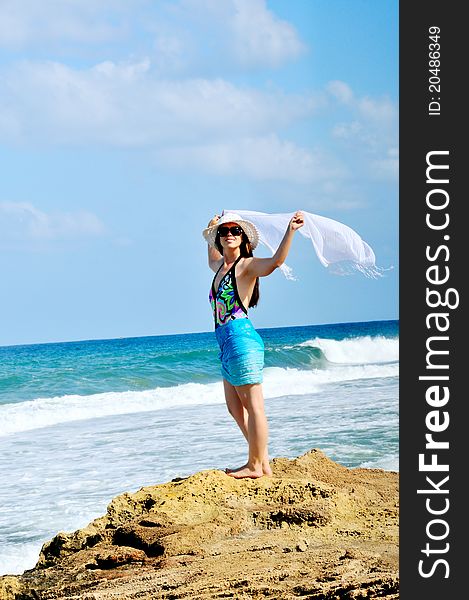 A girl stands on the beach and holding a white scarf that develops in the wind. A girl stands on the beach and holding a white scarf that develops in the wind