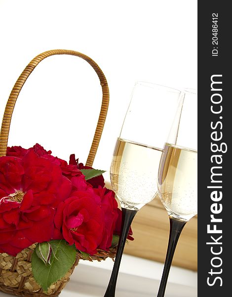 Beautiful basket full of red roses next to two glasses of champagne. isolated. Beautiful basket full of red roses next to two glasses of champagne. isolated