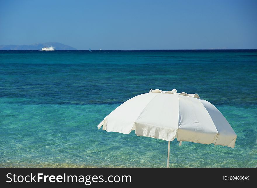 The Mediterranean beach whit white umbrella and boat.