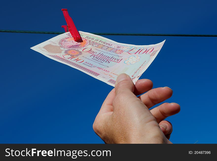 One hundred pound note being plucked from washing line against bright blue sky. One hundred pound note being plucked from washing line against bright blue sky.