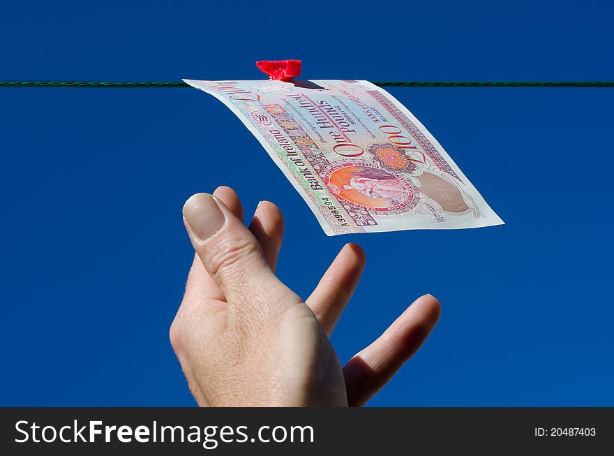 One hundred pound note just out of reach on a washing line against bright blue sky. One hundred pound note just out of reach on a washing line against bright blue sky.