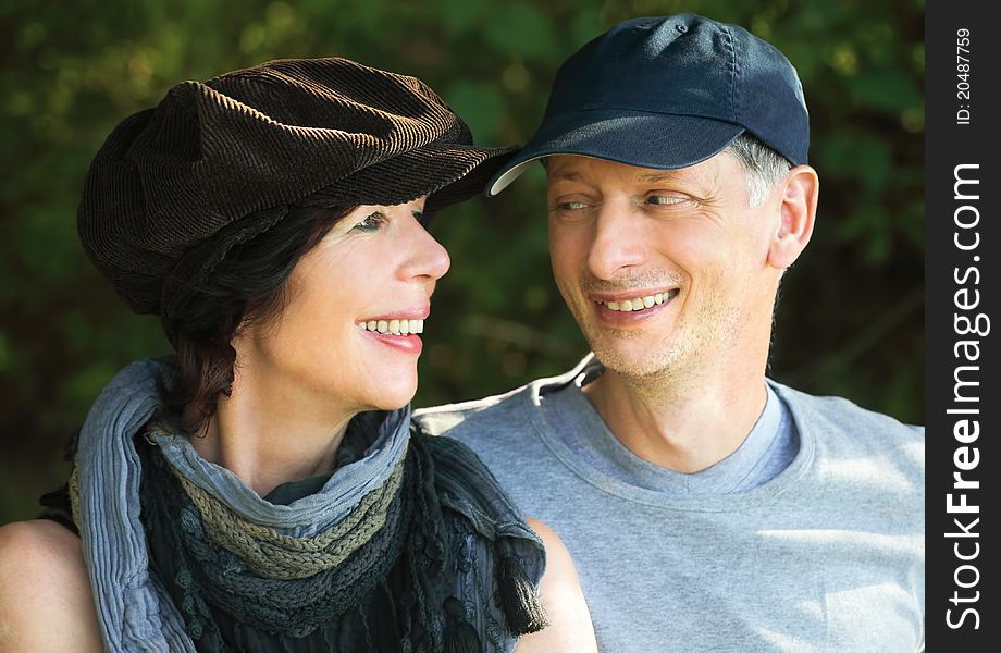Middleage couple with scarf and cap smiling at each other, outdoors. Middleage couple with scarf and cap smiling at each other, outdoors