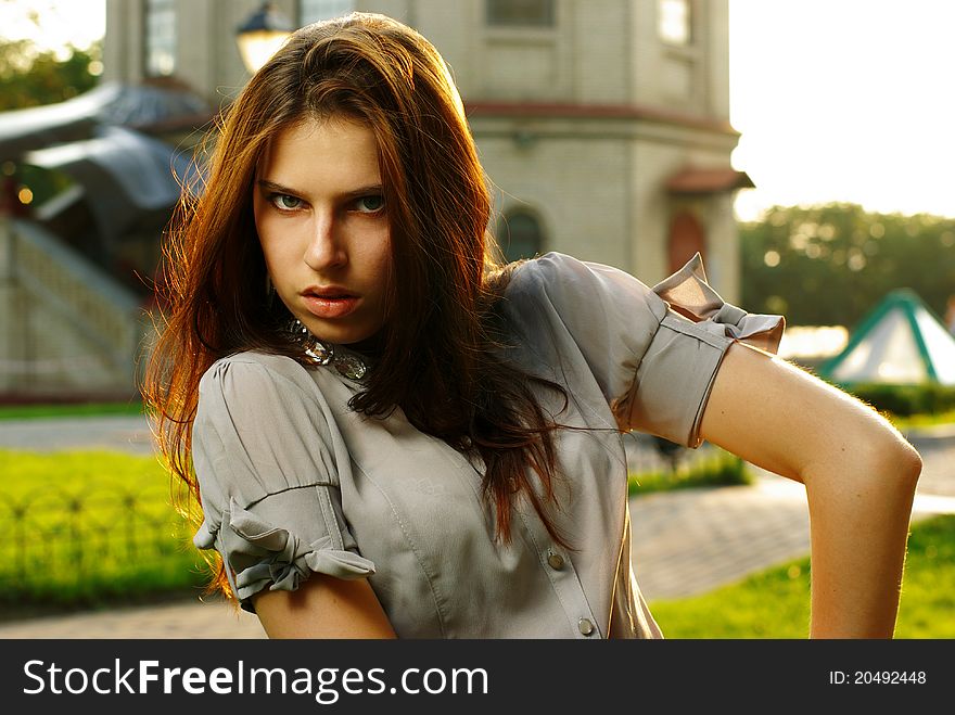 Portrait of a beautiful girl posing at the city street in sunset back light