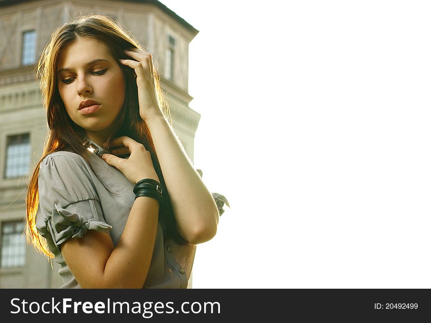 Portrait of a beautiful girl posing at the city street in sunset back light