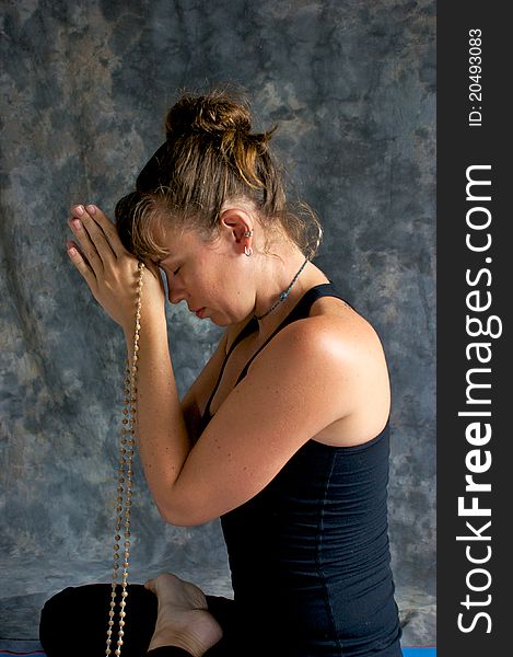 Studio portrait of beautiful young woman praying with beads, her eyes are closed and head bowed. Studio portrait of beautiful young woman praying with beads, her eyes are closed and head bowed.