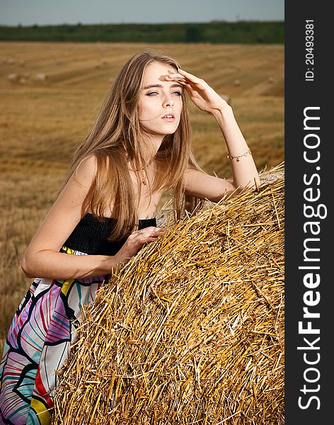 Young girl standing near haystack