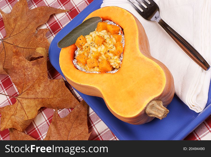 Half pumpkin filled with pumpkin risotto served on a blue plate. Half pumpkin filled with pumpkin risotto served on a blue plate