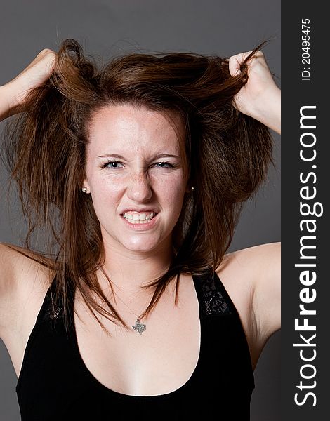 Caucasian female expresses her frustration by pulling at her hair in the studio. Caucasian female expresses her frustration by pulling at her hair in the studio