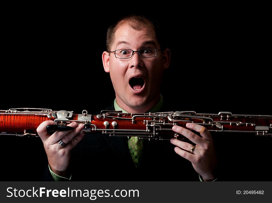 Caucasian male holds his bassoon with a surprised expression on his face in the studio. Caucasian male holds his bassoon with a surprised expression on his face in the studio