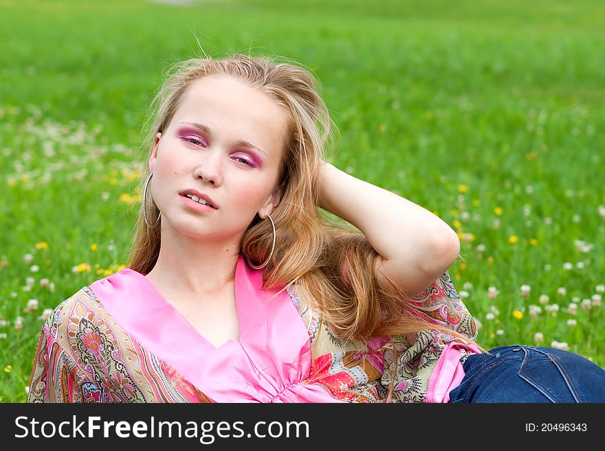 Portrait of a beautiful young woman on the grass in summer