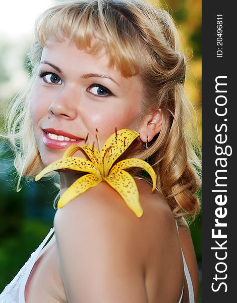 Smiling nice woman with yellow lily on shoulder