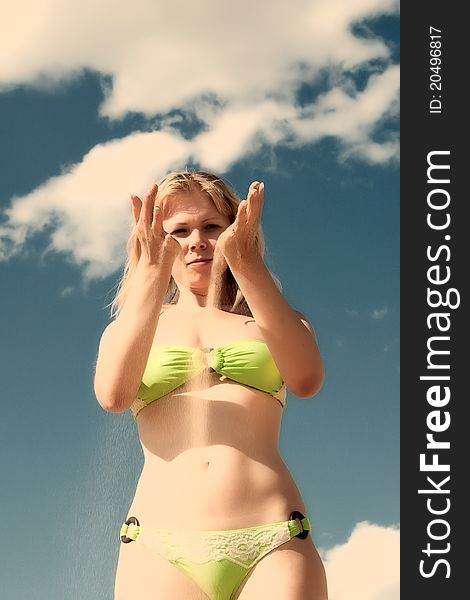 Smiling woman in bikini with sand trough fingers