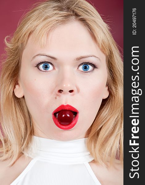 Surprised woman with cherry  in her mouth