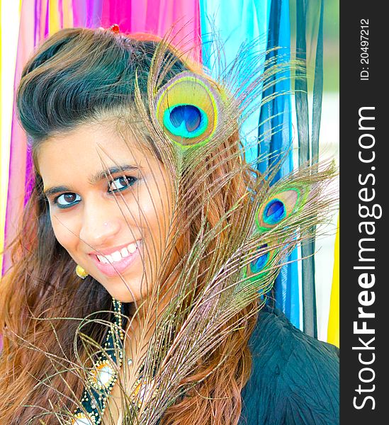 Young Pakistani model posing on a colorful background with peacock feathers. Young Pakistani model posing on a colorful background with peacock feathers