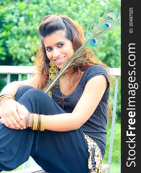 A young model posing with traditional indian peacock feathers in the outdoors. A young model posing with traditional indian peacock feathers in the outdoors