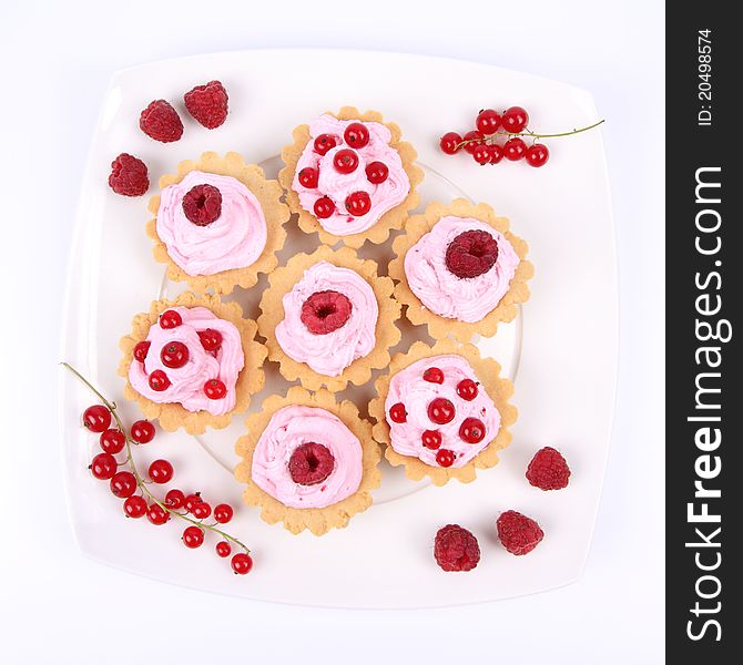 Tartlets with whipped cream and fruits - raspberries and redcurrants - on a plate