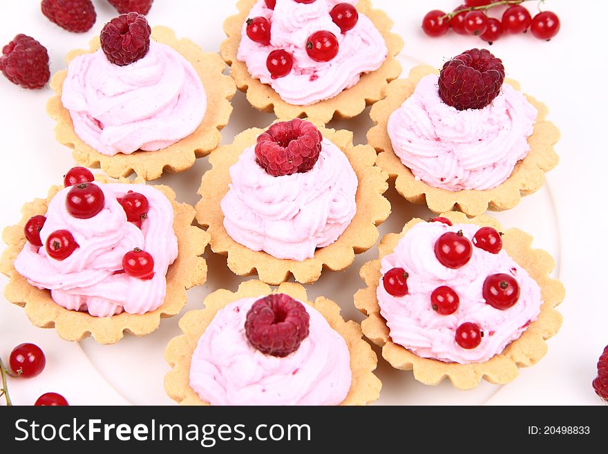 Tartlets with whipped cream and fruits - raspberries and redcurrants - on a plate