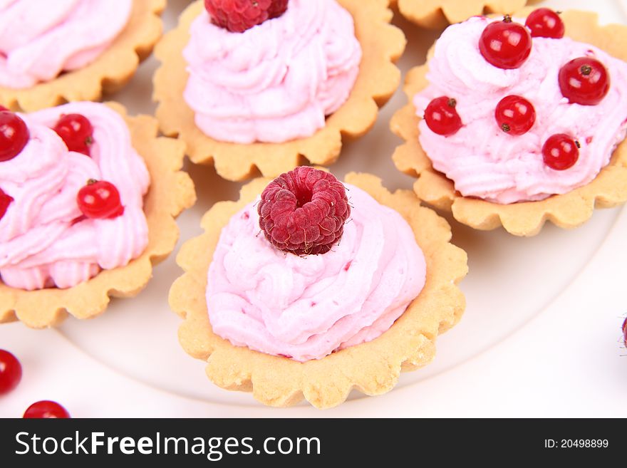 Tartlets with whipped cream and fruits - raspberries and redcurrants - on a plate