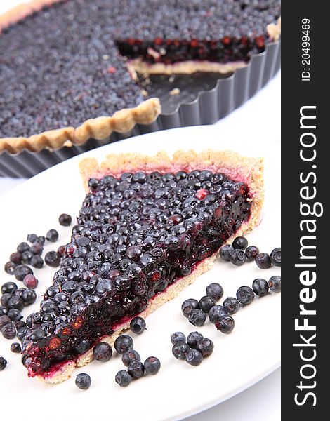 Blueberry Tart: a portion on a plate and in a tart pan on a white background