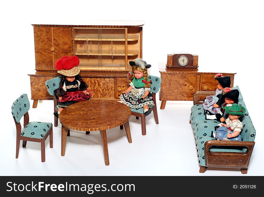 5 dolls in traditional European (I think they are Austrian but not sure) dresses sitting on chairs and couch round a table (old hand made furniture) with racks on the background. 5 dolls in traditional European (I think they are Austrian but not sure) dresses sitting on chairs and couch round a table (old hand made furniture) with racks on the background.